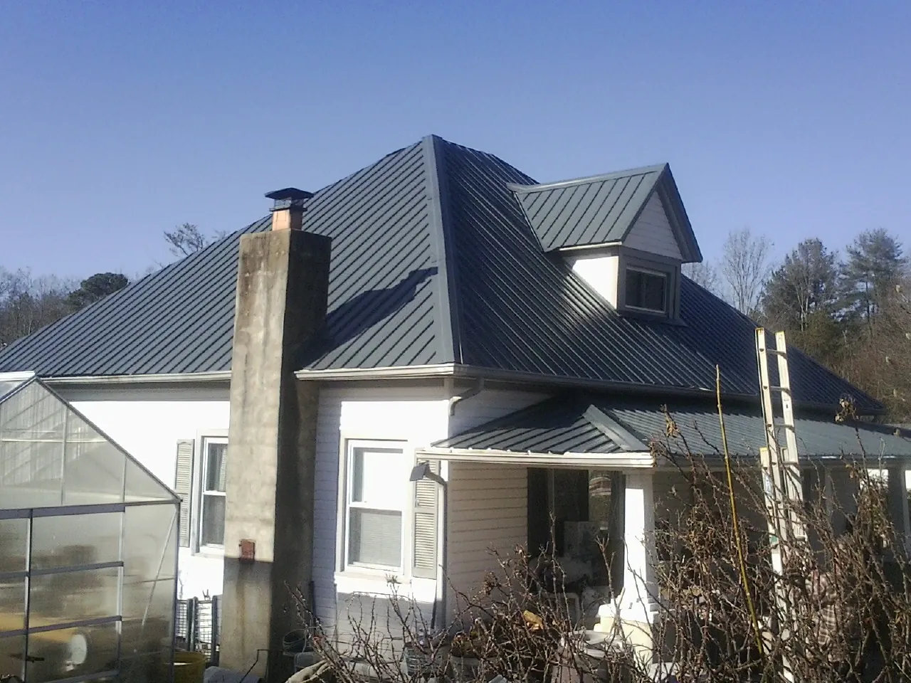Dark blue standing seam metal roof on a white farmhouse with dormer — Slate & Tile Roof Repair by Roofing Brothers in Chesterfield
